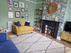 uma sala de estar com um sofá amarelo e uma lareira em Chic Edwardian Home With Garden em Kent