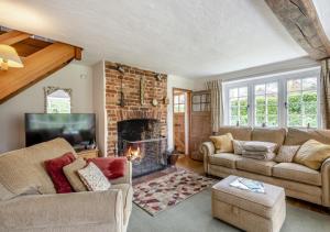 a living room with a couch and a fireplace at Clare Cottage in Melton Constable