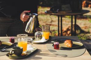 een tafel met borden met voedsel en sinaasappelsap bij Glamping Casa Esteval in Rocha Amarela