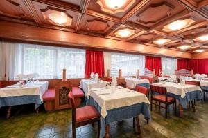 ein Restaurant mit weißen Tischen und Stühlen sowie roten Vorhängen in der Unterkunft Hotel Grohmann in Campitello di Fassa