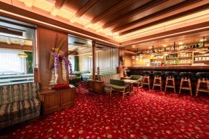 una camera con un bar con sedie e un tappeto rosso di Hotel Grohmann a Campitello di Fassa