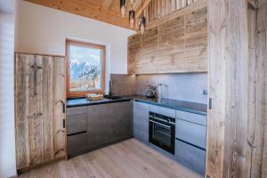 eine Küche mit Holzwänden und Arbeitsflächen sowie einem Fenster in der Unterkunft Chalets Hansleitner in Terenten