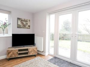 a living room with a flat screen tv and windows at The Brambles in Monmouth