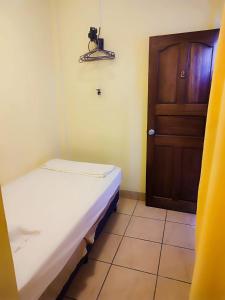a small room with a bed and a door at Hostel Tropical and CoWorking in San Juan del Sur