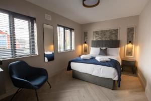 a bedroom with a bed and a chair and windows at The Abbeygate Townhouse in Galway