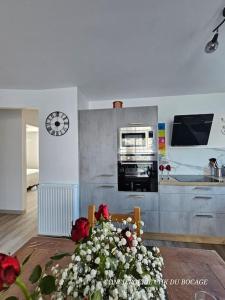 eine Küche mit einem Tisch mit Blumen darauf in der Unterkunft Chez Tina jolie maison à 12 min du Puy du Fou in Les Herbiers