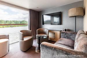 ein Wohnzimmer mit einem Sofa, Stühlen und einem TV in der Unterkunft KD Hotelschiff Messe und Stadion in Düsseldorf