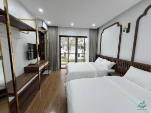 a hotel room with two beds and a tv at Rosa Villa - Sonasea Vân Đồn in Cái Rồng