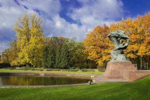a statue in a park next to a pond at Parrot Dream.Stunning 2 bedrooms near metro&center in Warsaw