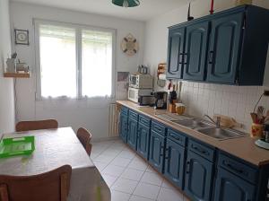 a kitchen with blue cabinets and a table and a window at Apparthaubourdin in Haubourdin