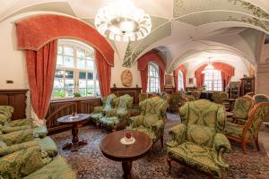 a living room with chairs and a chandelier at Hotel Dolomiti Schloss in Canazei