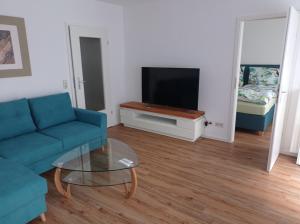 a living room with a blue couch and a tv at Ferienwohnung Mönchgut II in Middelhagen