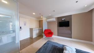 a room with a red chair and a television at Flat no Brasília Lider, 14º Andar in Brasília