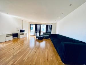 a living room with a black couch and wooden floors at Riverside 2 Bed Apartment with Free Parking in London