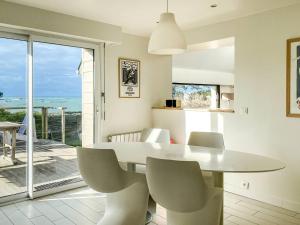 ein weißes Esszimmer mit Tisch und Stühlen in der Unterkunft Superbe villa à Trébeurden pour 11 personnes avec vue sur mer, jardin et WIFI - FR-1-368-327 in Trébeurden