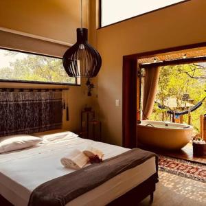 Cabanas da Mata - Cabana Candeia - Casa Branca/MG في كازا برانكا: غرفة نوم بسرير وحوض ونافذة