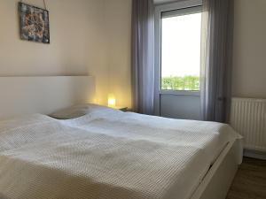 a white bed in a bedroom with a window at Haus Meeresglück Seeigel in Dahme