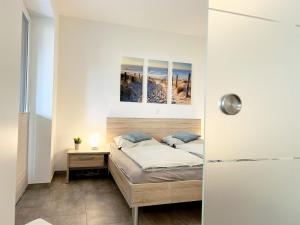 a bedroom with a bed and a nightstand with a bed and a picture at Apartment Oase am Meer, Am Alten Deich 18 in Dangast