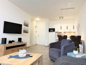 a living room with a couch and a tv at Apartment Oase am Meer, Am Alten Deich 18 in Dangast