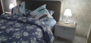 a bed with a blue comforter and a night stand with a lamp at LUX & VIP apartment at Berges du Lac 2 Tunis in La Goulette