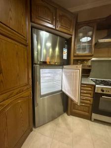a kitchen with a stainless steel refrigerator and wooden cabinets at 3bedroom apart at-Al Kursi in Amman