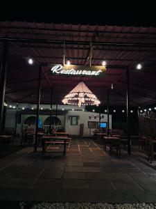een restaurant met houten tafels en een verlicht bord bij Seven Tales in Anjuna