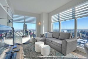 uma sala de estar com um sofá, cadeiras e janelas em Spectacular Skyline Views - Downtown Montreal - Luxury Condo & Penthouse em Montreal