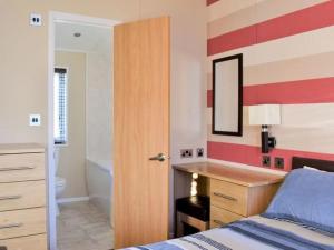 a bedroom with a bed and a desk and a bathroom at Victory Lodge 2 Bedroom - Sleeps 6 - Bron-Y-Wendon Holiday Park in Llanddulas
