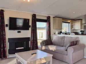 a living room with a couch and a tv at Victory Lodge 2 Bedroom - Sleeps 6 - Bron-Y-Wendon Holiday Park in Llanddulas