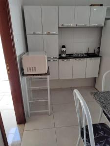 a kitchen with white cabinets and a table with a laptop on it at Casa de Temporada Isaura in Olímpia