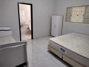 a white room with a bed and a bathroom at Casa de Temporada Isaura in Olímpia