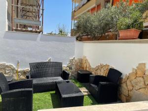 een patio met stoelen, een tafel en een muur bij Civico 8 Alexander in Alghero