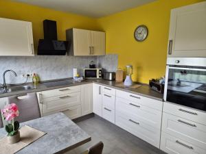 a kitchen with white cabinets and a clock on the wall at Ferienhaus Siggi in Walow