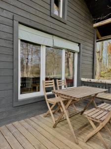 a wooden table and two chairs on a deck at PLŪSME Restart House in Lielstraupe
