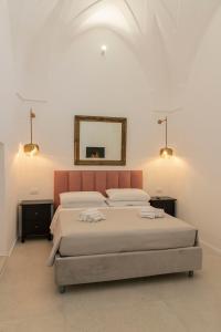 1 Schlafzimmer mit 2 Betten und einem Wandspiegel in der Unterkunft Palazzo AD 1892 - SUITES & SPA in Ostuni