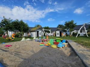 un parque infantil con muchos juguetes en la arena en Rodzinne Rusinowo, en Rusinowo
