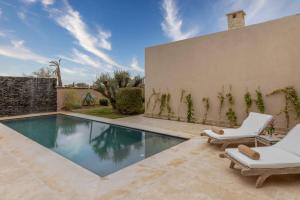 a swimming pool with two lounge chairs next to a wall at Ksar Char-Bagh Small Luxury Hotels in Marrakesh