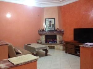 een woonkamer met een open haard en een televisie bij Location Mohammedia Mannesman Plages in Mohammedia