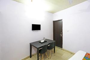 a room with a black table and chairs and a television at Twamev Punjabi Bagh in New Delhi