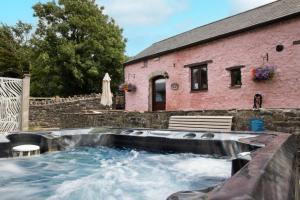 una vasca idromassaggio di fronte a una casa rosa di The Granary a Bridgend