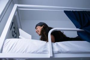 a woman sitting on top of a bunk bed at Bovisa Urban Garden in Milan