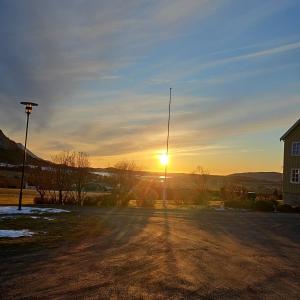 een zonsondergang met een paal in het midden van een weg bij Rødseth gårdsovernatting Hytter in Molde