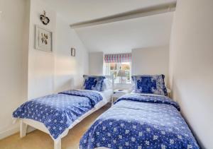 two beds in a room with blue and white sheets at Rose Cottage in Sedgeford