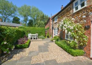 a garden with a bench in front of a building at Rose Cottage in Sedgeford