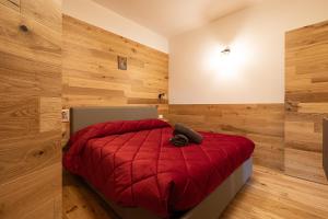 una camera con letto rosso e pareti in legno di Chalet Ponciai [10min sky slopes] a Dorga
