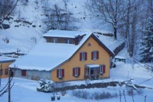 a yellow house with snow on top of it at La Ruche in La Bresse