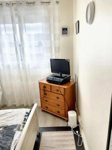 - une chambre avec un lit et une télévision sur une commode dans l'établissement Villa de 4 chambres avec jardin clos et wifi a Elancourt, à Élancourt
