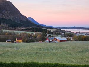 a field with a town and a lake and mountains at Rødseth gårdsovernatting Hytter in Molde