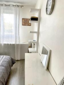 1 dormitorio con cama, espejo y reloj en Villa de 4 chambres avec jardin clos et wifi a Elancourt, en Élancourt