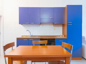 a kitchen with blue cabinets and a wooden table at Casa Acquachiara - a due passi dalla spiaggia in Monte Argentario